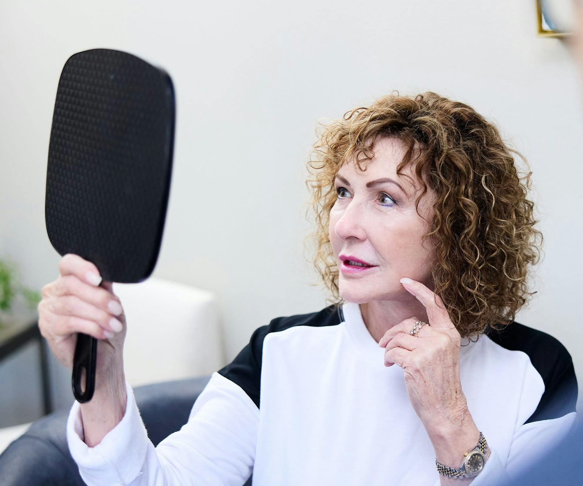 patient pointing to her face while looking in mirror