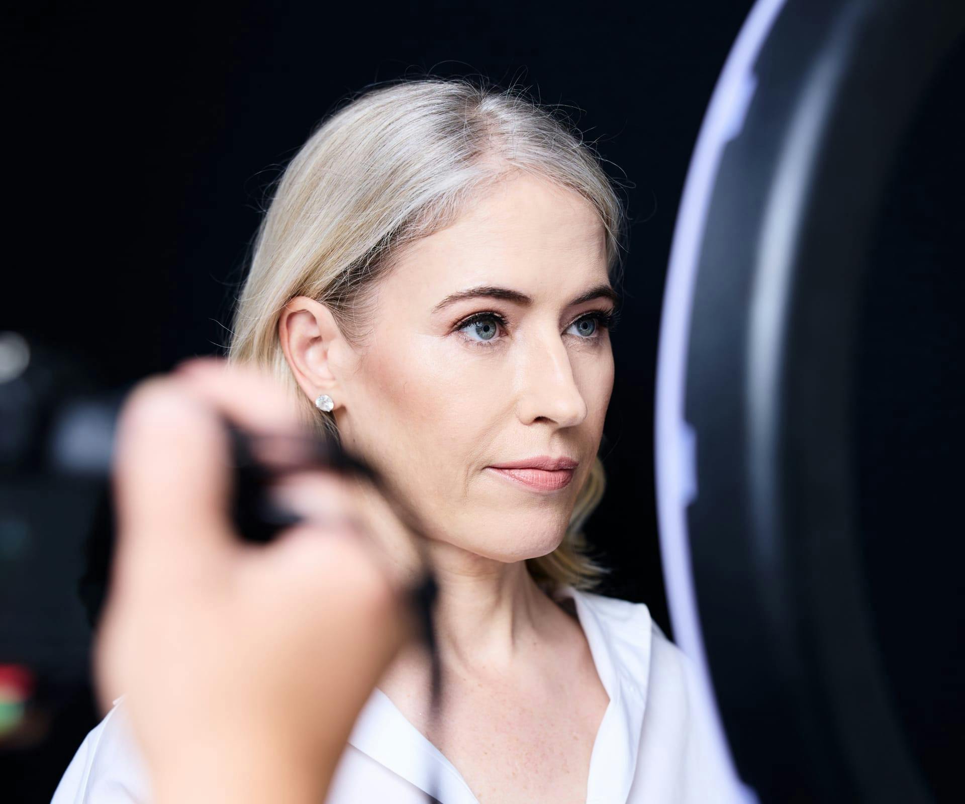 Woman looking in illuminated mirror